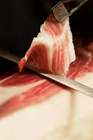 A piece of Cinco Jotas jam&oacute;n Iberico is carved