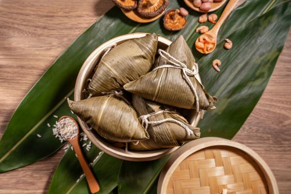 Zongzi, steamed rice dumplings on wooden table bamboo leaves