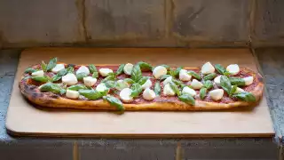 A freshly-made pizza with mozzarella, tomato and basil