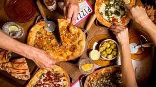 London's best pizza | people cutting into Flat Earth pizza