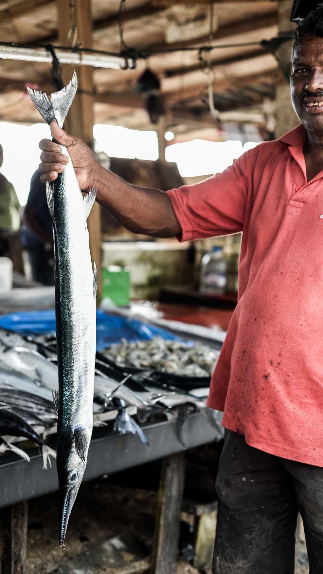 A man hoisting an usi kola fish at a market