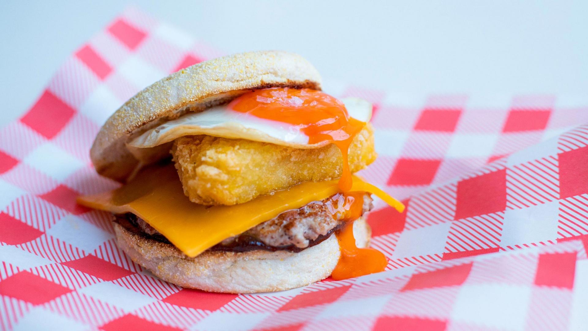 Best brunch London: Norman's Cafe in Tufnell Park's breakfast muffin, with sausage patty, a hash brown, a fried egg and red leicester cheese
